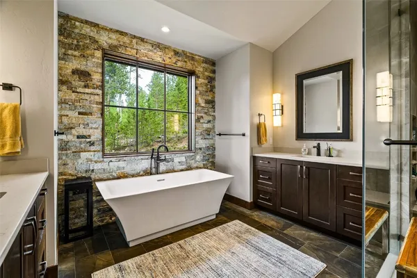 a spacious bathroom with a bathtub double sink and mirror