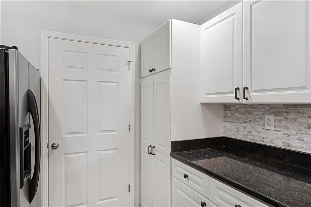 220 Renaissance Parkway Northeast, Unit 2119 Atlanta, GA 30308 - Photo 5 of 19 a kitchen with granite countertop white cabinets and refrigerator
