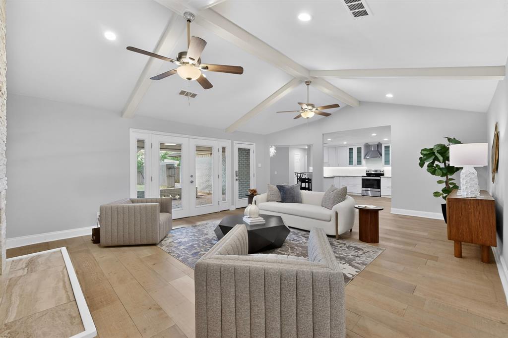 7631 Meadow Road Dallas, TX 75230 - Photo 9 of 40 A cozy family room with a high ceiling, two ceiling fans and a fireplace, with access to the patio at the back.