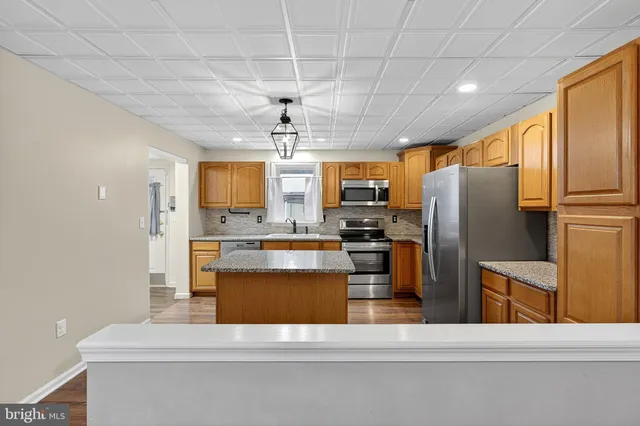 a kitchen with stainless steel appliances kitchen island granite countertop a refrigerator a stove top oven a sink and dishwasher