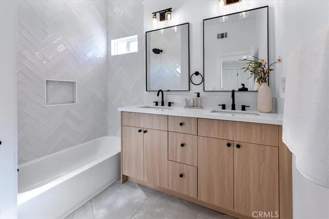 a bathroom with a double vanity sink mirror and bathtub
