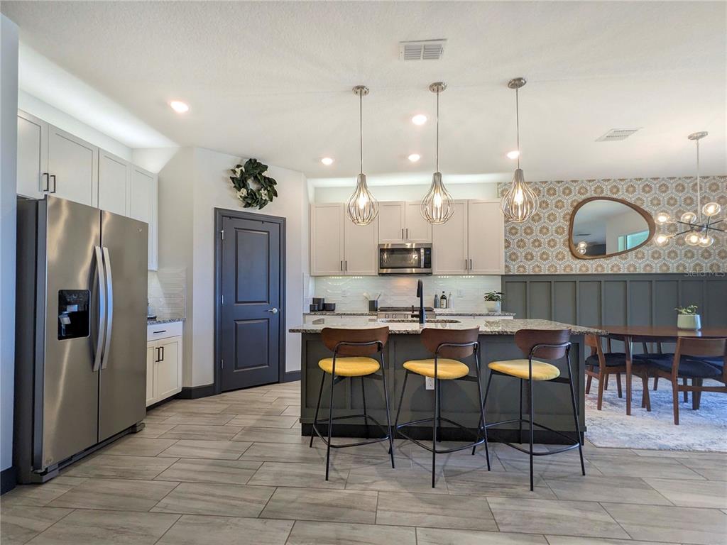 3324 Big Sky Way Lakewood Ranch, FL 34211 - Photo 5 of 49 a dining hall with stainless steel appliances kitchen island granite countertop a table chairs and a refrigerator