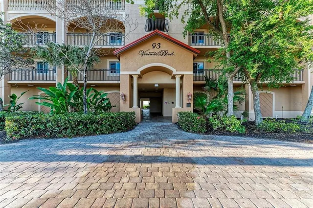 a view of a brick house with plants and large tree