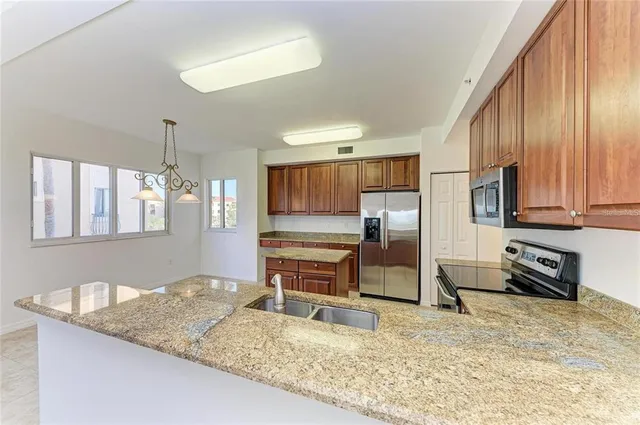 a kitchen with stainless steel appliances granite countertop a sink refrigerator and cabinets