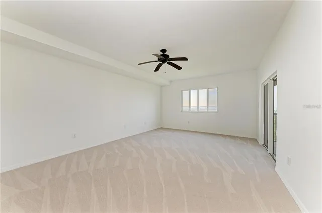 an empty room with chandelier fan and windows
