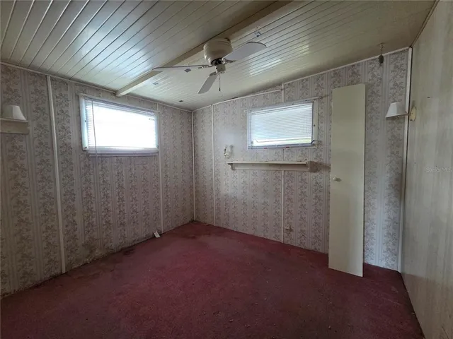 an empty room with closet and a ceiling fan