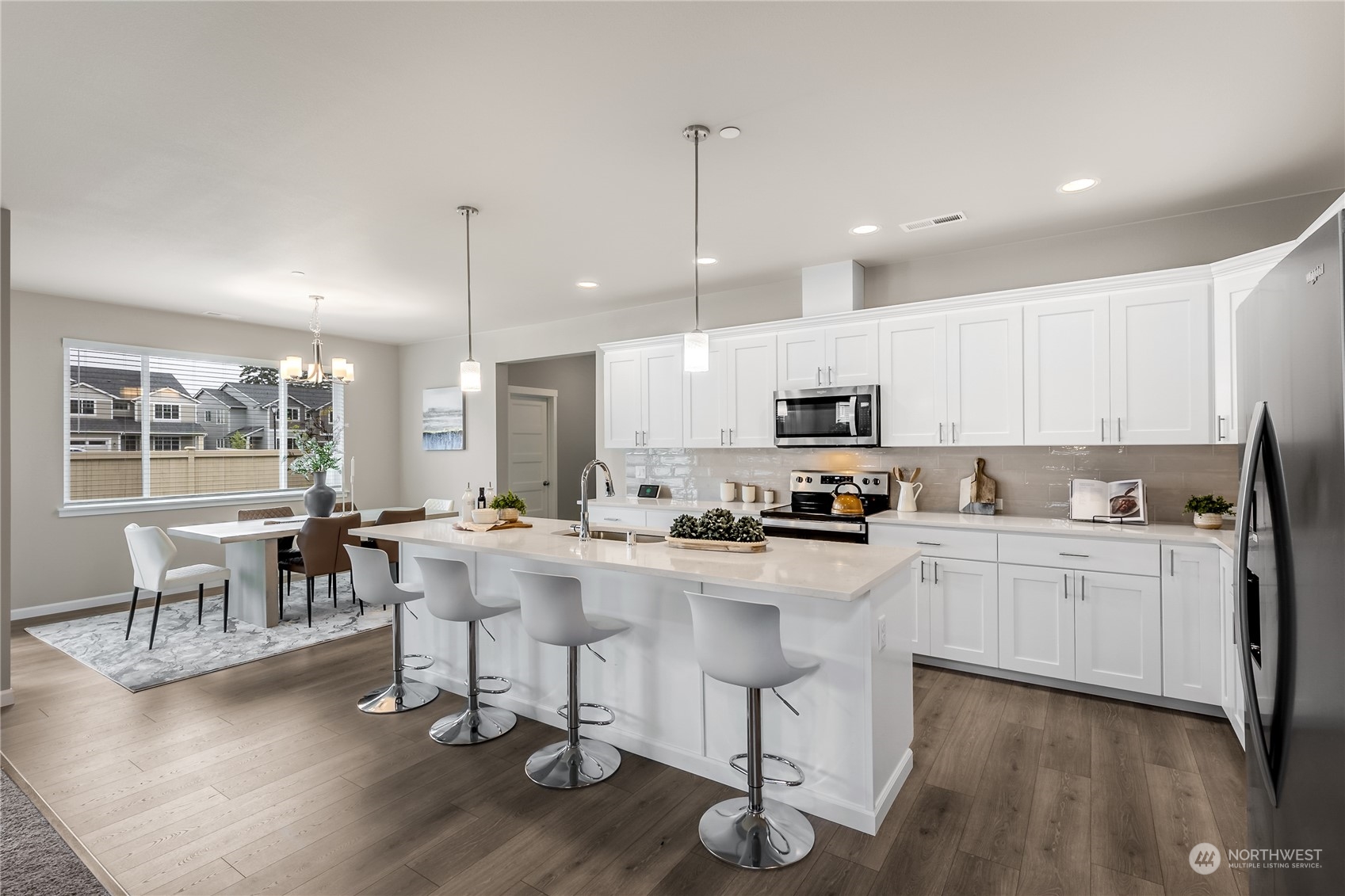 3040 Stephanie Loop Northeast Lacey, WA 98516 - Photo 3 of 14 a kitchen with stainless steel appliances granite countertop a stove top oven a sink a dining table and chairs with wooden floor