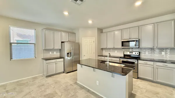 a kitchen with granite countertop a stove sink microwave and refrigerator