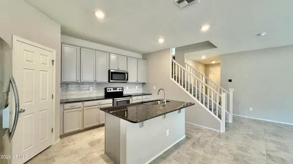 a kitchen with granite countertop a sink a stove top oven and cabinetry