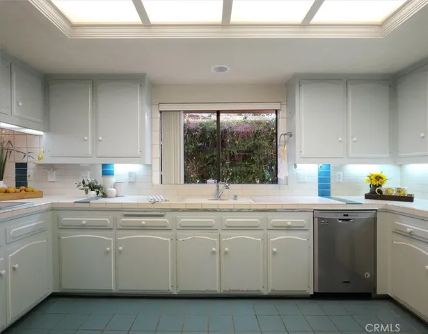 a kitchen with white cabinets appliances a sink and a window