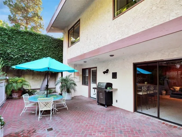 a view of a patio with table and chairs under an umbrella with wooden fence