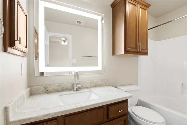 a bathroom with a granite countertop sink toilet a mirror and bathtub