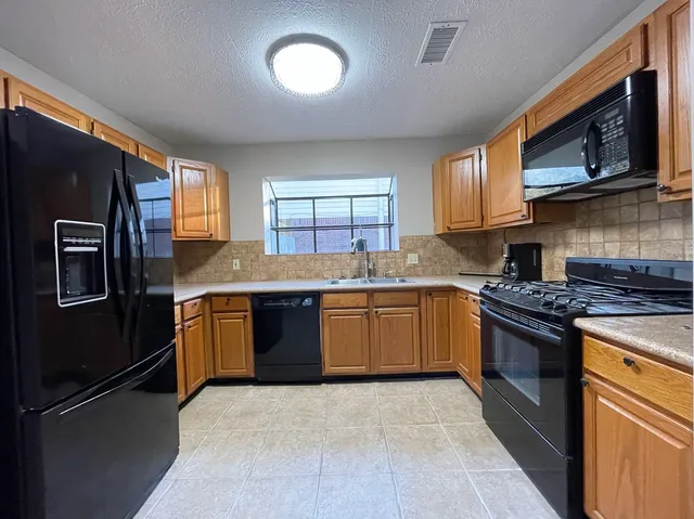 a kitchen with stainless steel appliances granite countertop a refrigerator stove top oven and sink