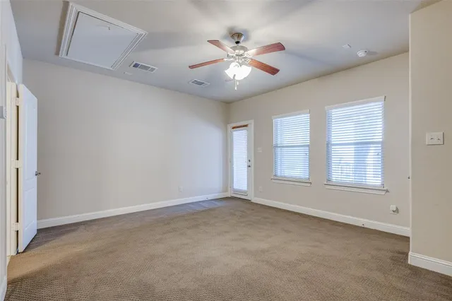 an empty room with chandelier fan and windows