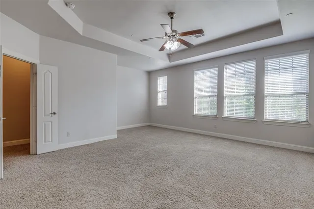 a view of an empty room with chandelier fan and fire place