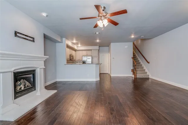a view of a kitchen and an empty room with wooden floor a fireplace