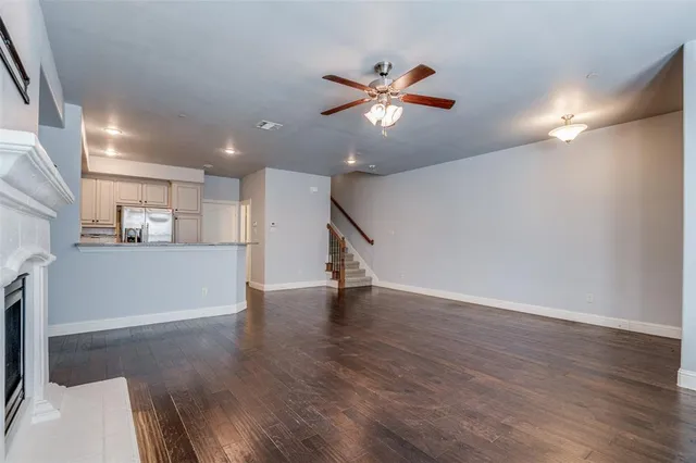 a view of an empty room with wooden floor and a ceiling fan