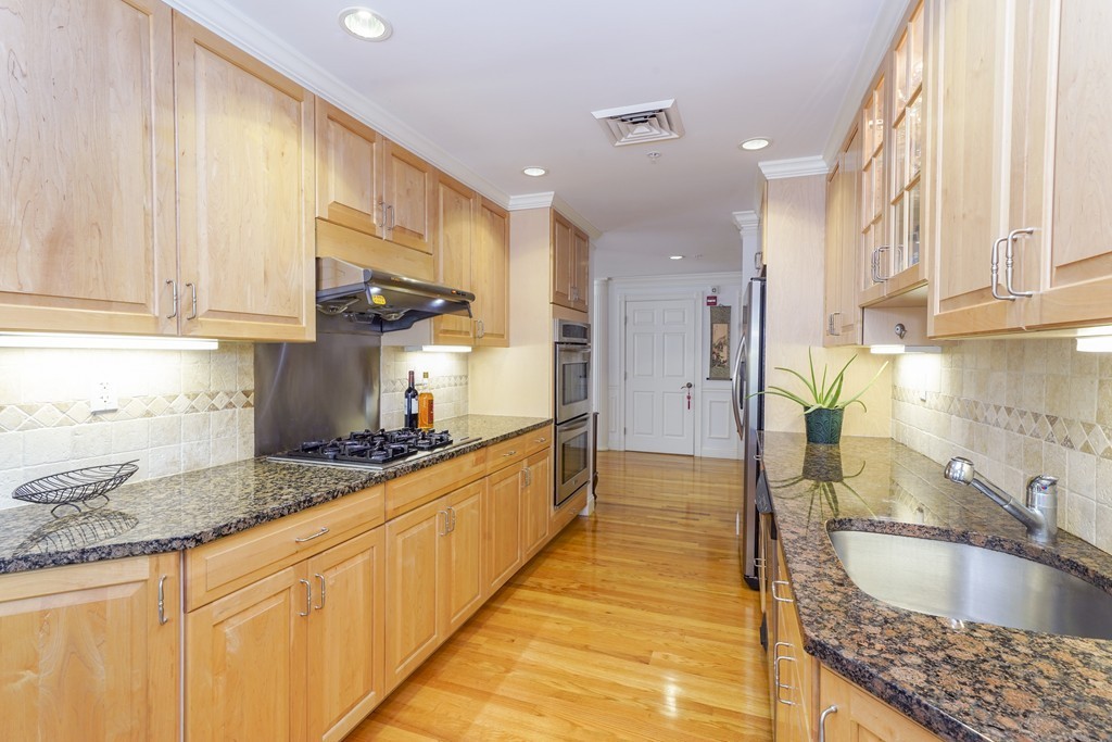 75 Winchester Street, Unit 301 Brookline, MA 02446 - Photo 5 of 8 a kitchen with stainless steel appliances granite countertop a sink a stove and a wooden cabinets