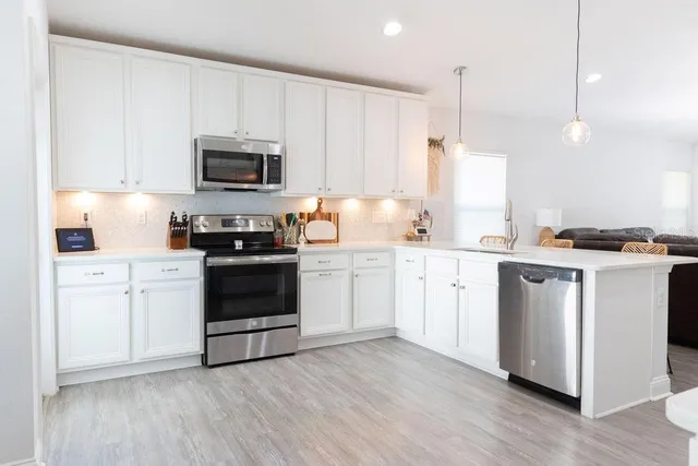 a kitchen with a white stove top oven and white wooden cabinets