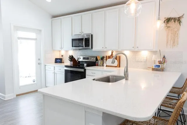 a kitchen with a sink a stove and white cabinets