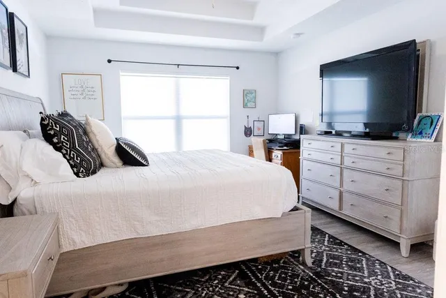 a bedroom with a large bed and a flat tv screen on dresser