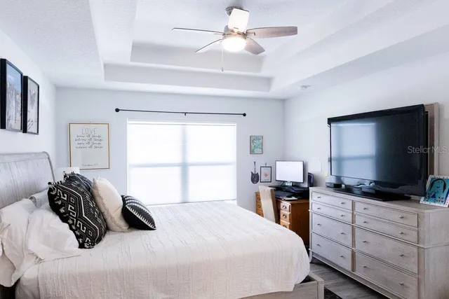 a bedroom with a large bed and a flat tv screen on dresser