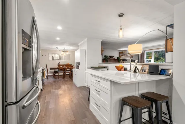a kitchen with stainless steel appliances a dining table chairs stove and refrigerator