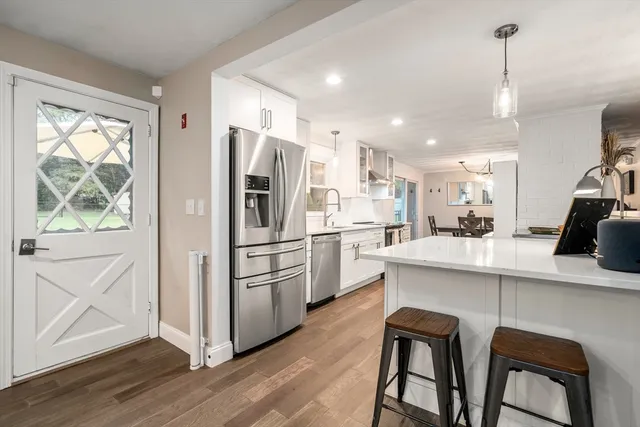 a kitchen with stainless steel appliances a refrigerator a stove a sink dishwasher a oven with white cabinets and wooden floor