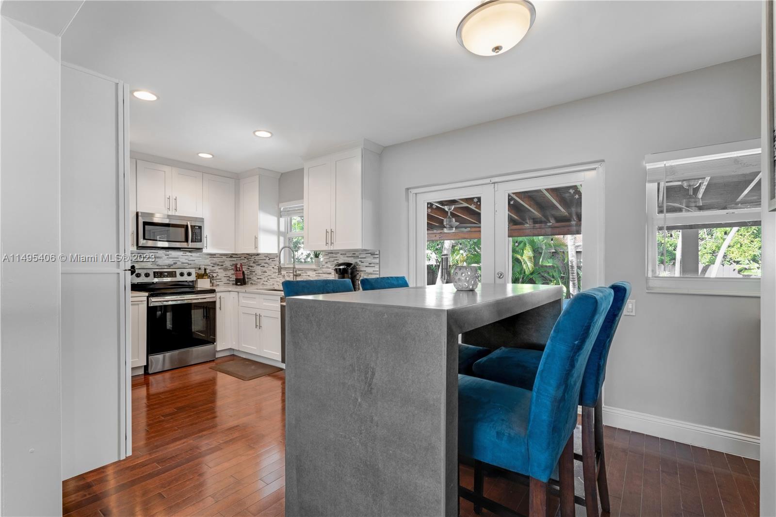 2465 Southwest 21st Terrace Miami, FL 33145 - Photo 13 of 45 a kitchen with stainless steel appliances granite countertop a stove top oven a sink dishwasher a dining table and chairs with wooden floor