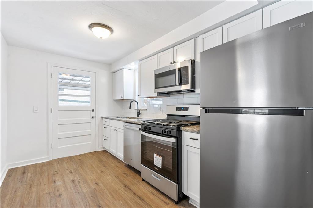 2041 Lindsay Road Pittsburgh, PA 15221 - Photo 9 of 24 a kitchen with a stove a microwave and white cabinets