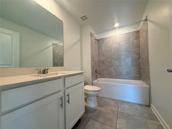 a bathroom with a bathtub shower sink vanity mirror and toilet