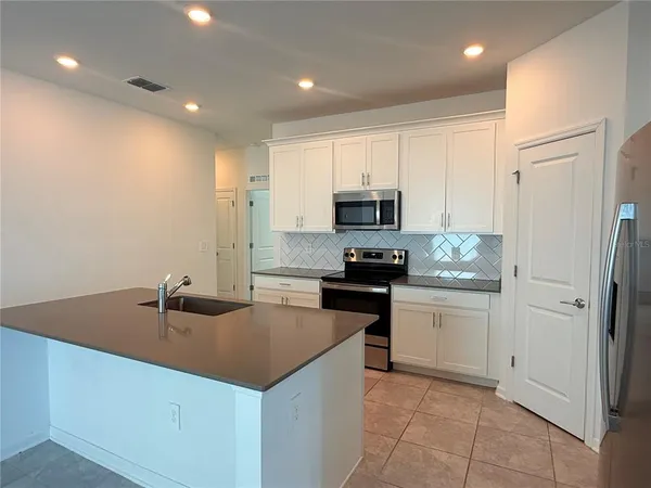 a kitchen with stainless steel appliances granite countertop a sink a stove a refrigerator a microwave a counter top and cabinets