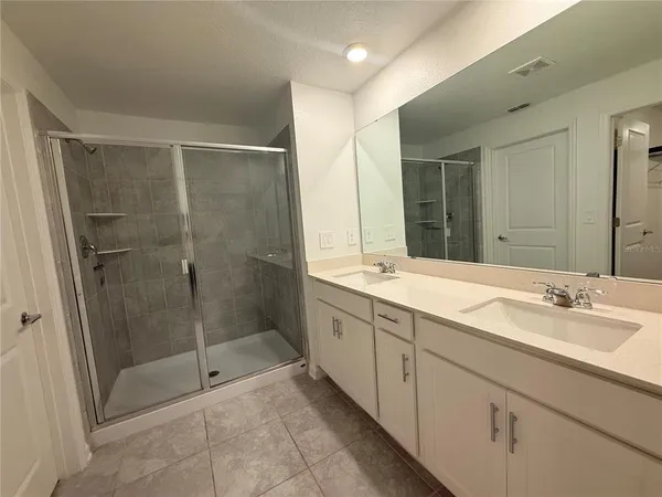 a spacious bathroom with a shower sink and mirror