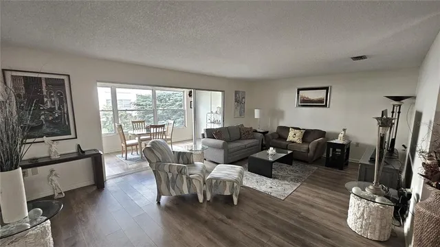 a living room with furniture a large window and wooden floor