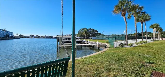 a view of a lake with a bench and trees in the background