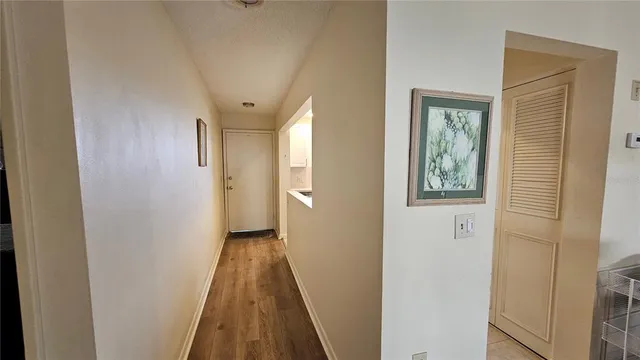 a view of a hallway with wooden floor and a bathroom