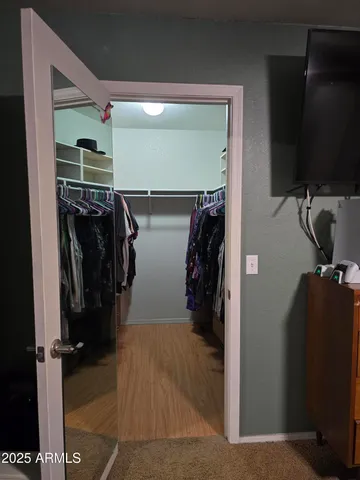 a view of walk in closet with clothes and shoes