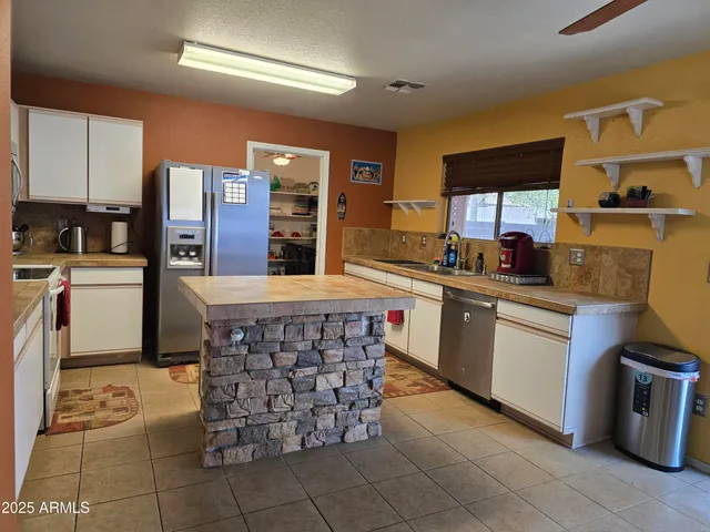 a kitchen with kitchen island granite countertop a sink counter top space appliances and cabinets