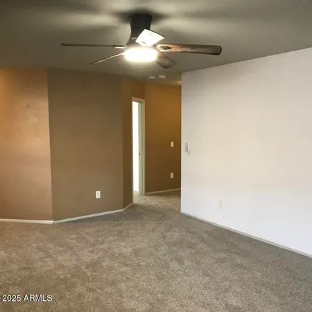 a view of an empty room and a chandelier fan