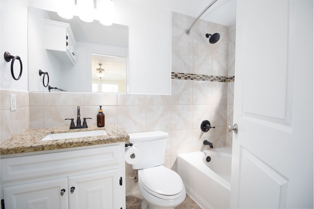 5201 Chapman Street Houston, TX 77009 - Photo 19 of 30 a bathroom with a granite countertop sink toilet mirror vanity and bathtub