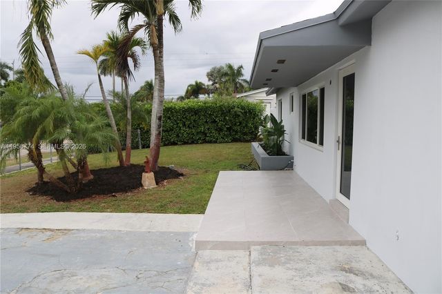 a view of a house with a yard and palm trees