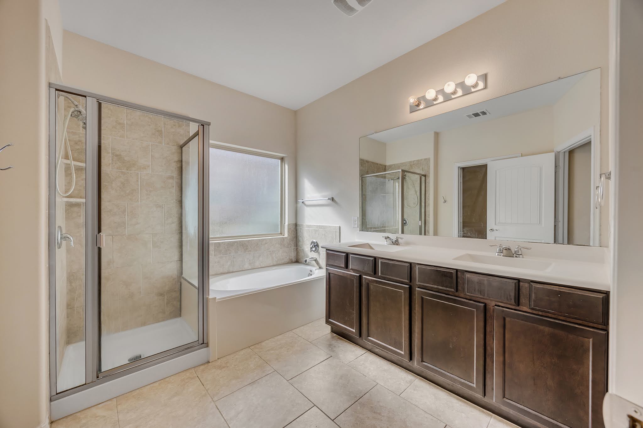 7212 Vail Ridge Street Austin, TX 78744 - Photo 17 of 26 Luxurious primary bath with a spacious shower, a separate soaking tub, and a dual vanity.