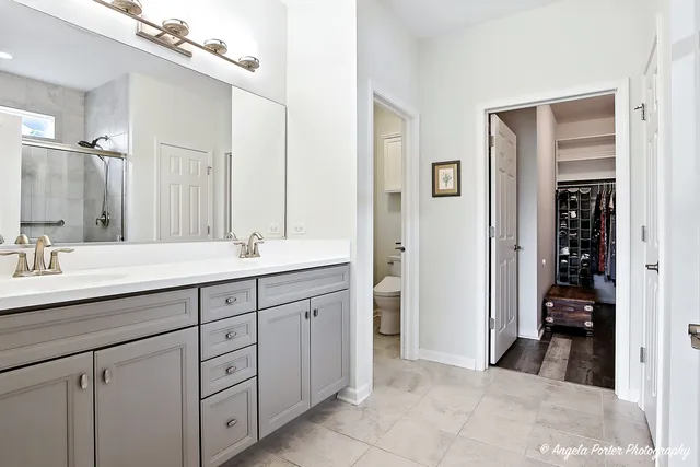 a spacious bathroom with a double vanity sink a mirror and shower