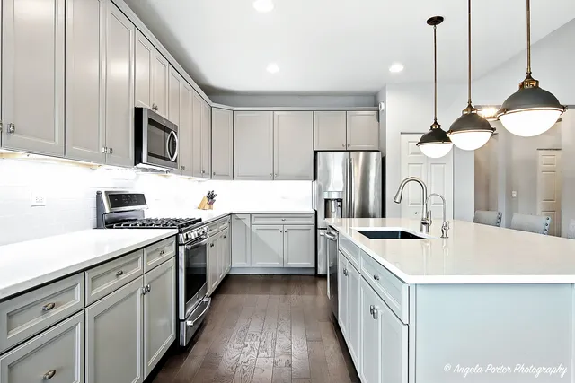 a kitchen with a sink dishwasher a stove top oven a refrigerator with island and cabinets