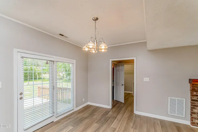 a view of a room with wooden floor chandelier and windows