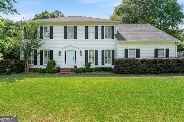 a front view of a house with a yard and trees