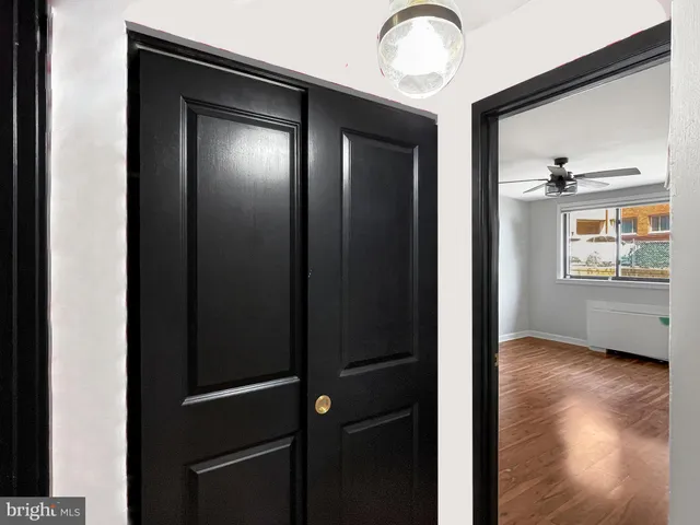 a view of an empty room with wooden floor and a window