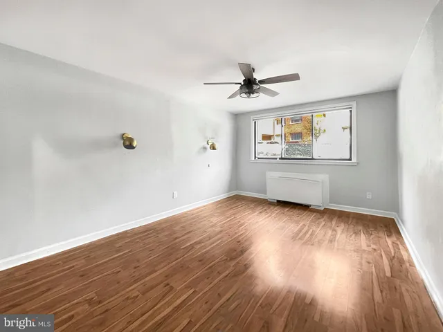 a view of empty room with wooden floor and fan