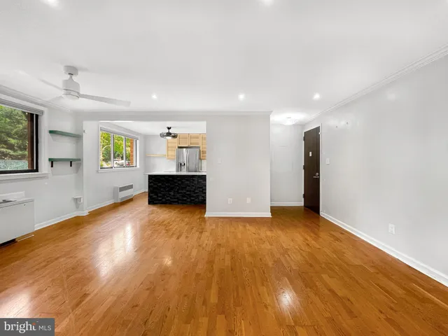 a view of an empty room with window and wooden floor