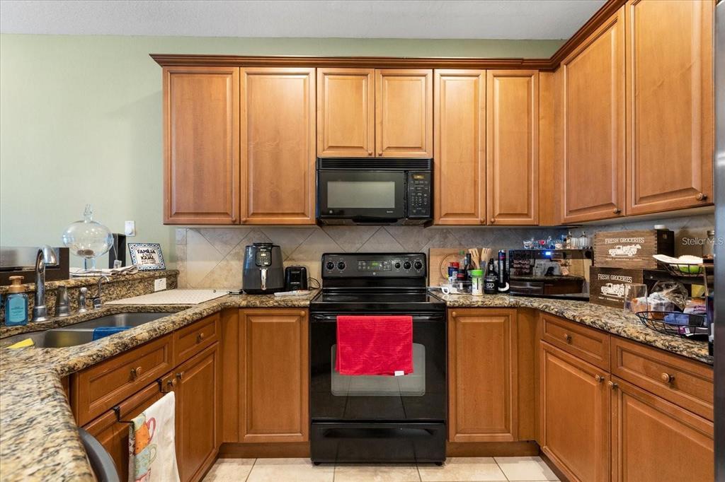 3115 Capri Isle Way Orlando, FL 32835 - Photo 15 of 40 a kitchen with stainless steel appliances granite countertop a stove a sink and a microwave